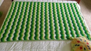 a ripple-striped blanket in shades of green with yellow and white