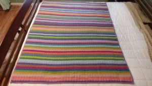 a multicolored striped blanket on a bed