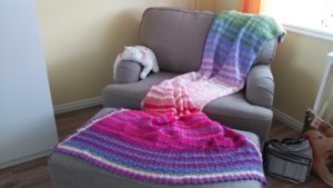 Sweet Pea Blanket CAL - a multicolored striped blanket draped over an armchair and ottoman