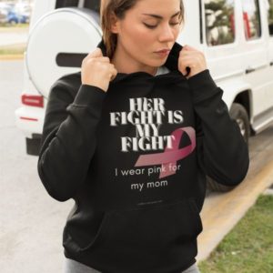 Mockup of a trendy woman wearing a hoodie that reads: Her fight is my fight. I wear pink for my mom.