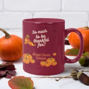 Mockup featuring a mug surrounded by pumpkins. Design on mug reads: So much to be thankful for! Breast cancer survivor