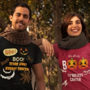 T-shirt mockup of a couple at a park during fall. One of the designs reads: BOO! Scare away breast cancer