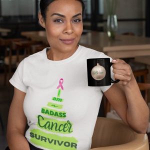 T-shirt mockup of a woman sitting on a chair holding a mug. T-shirt design featuring a Christmas tree reads: I am a badass cancer survivor